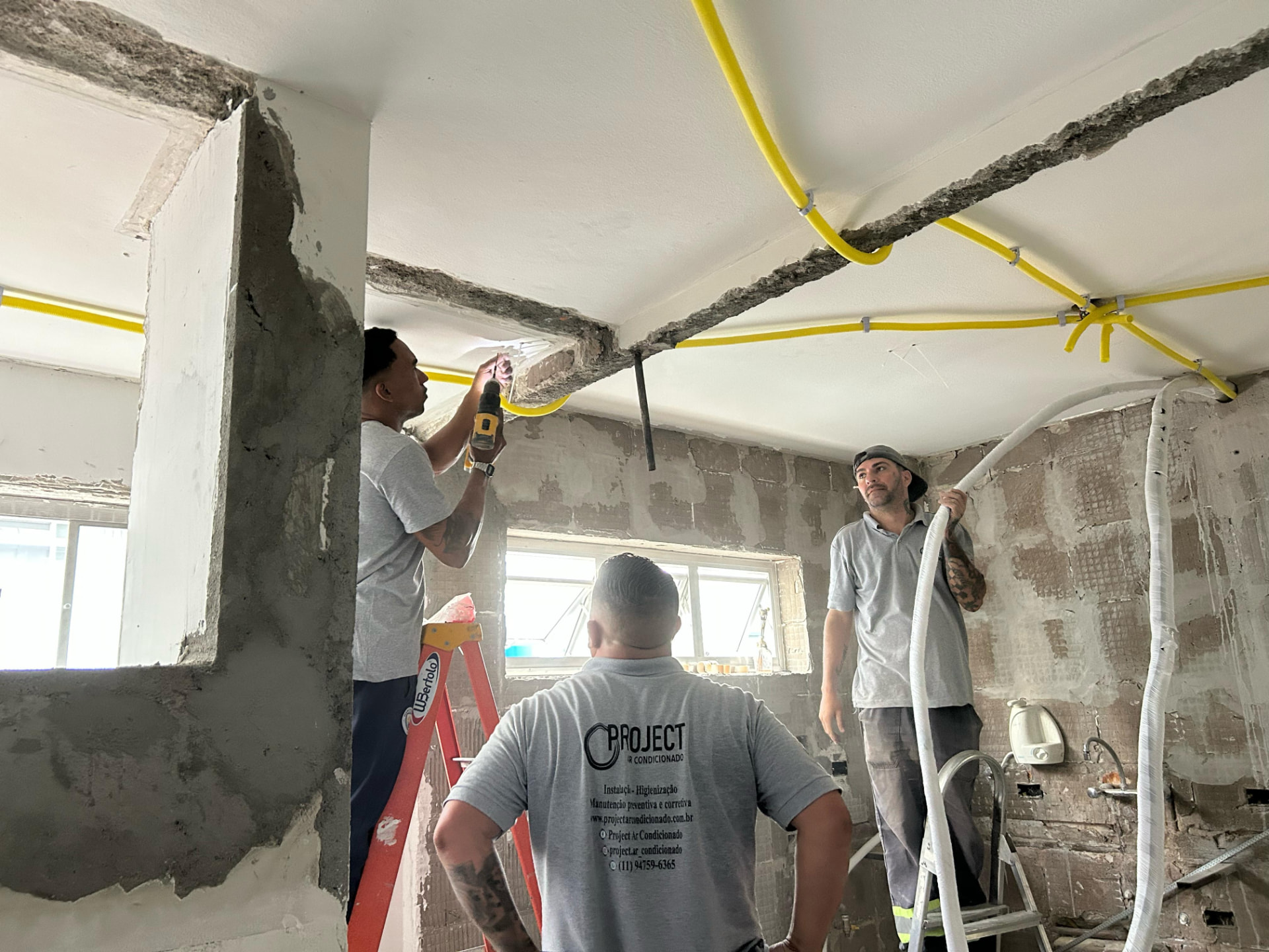 Equipe instalando infraestrutura de ar condicionado em obra